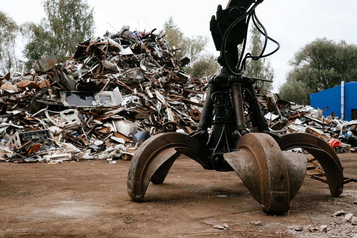 Hydraulic grab machine lifting metal debris at a large industrial scrap yard